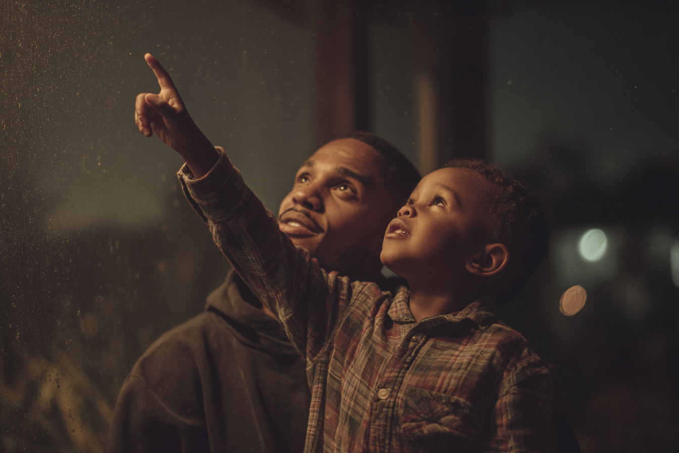 Father and son looking up at the sky at night.